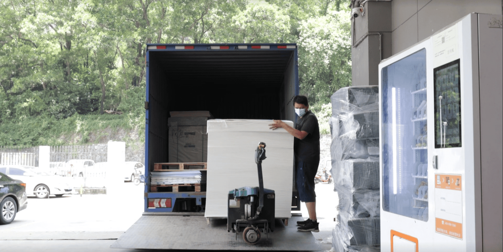 Cadro folding hydraulic tail lift deployed in urban multi-stop delivery scenario — rear view of electric van with platform lowered, cargo pallet being loaded, city street backdrop with delivery route stops